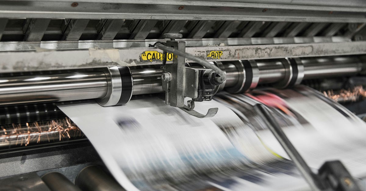 A specialized production printer in use, producing posters at high speed.