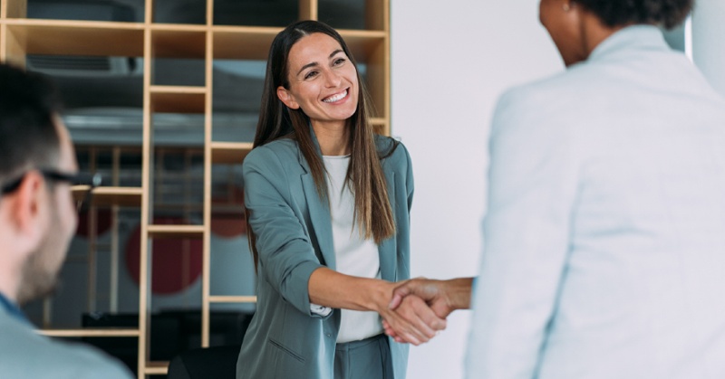 Business woman shaking hand of other business woman.