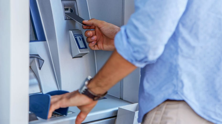 A man using his PIN at an ATM illustrates a common, everyday example of how easy multi-factor authentication can be.