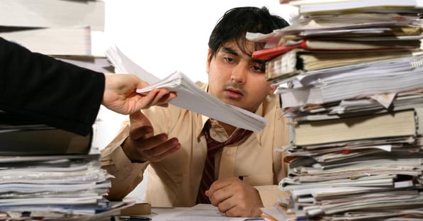 An exhausted employee is overwhlemed by paper-based workflows, which can be resolved with proper printer workflow automation tools. 