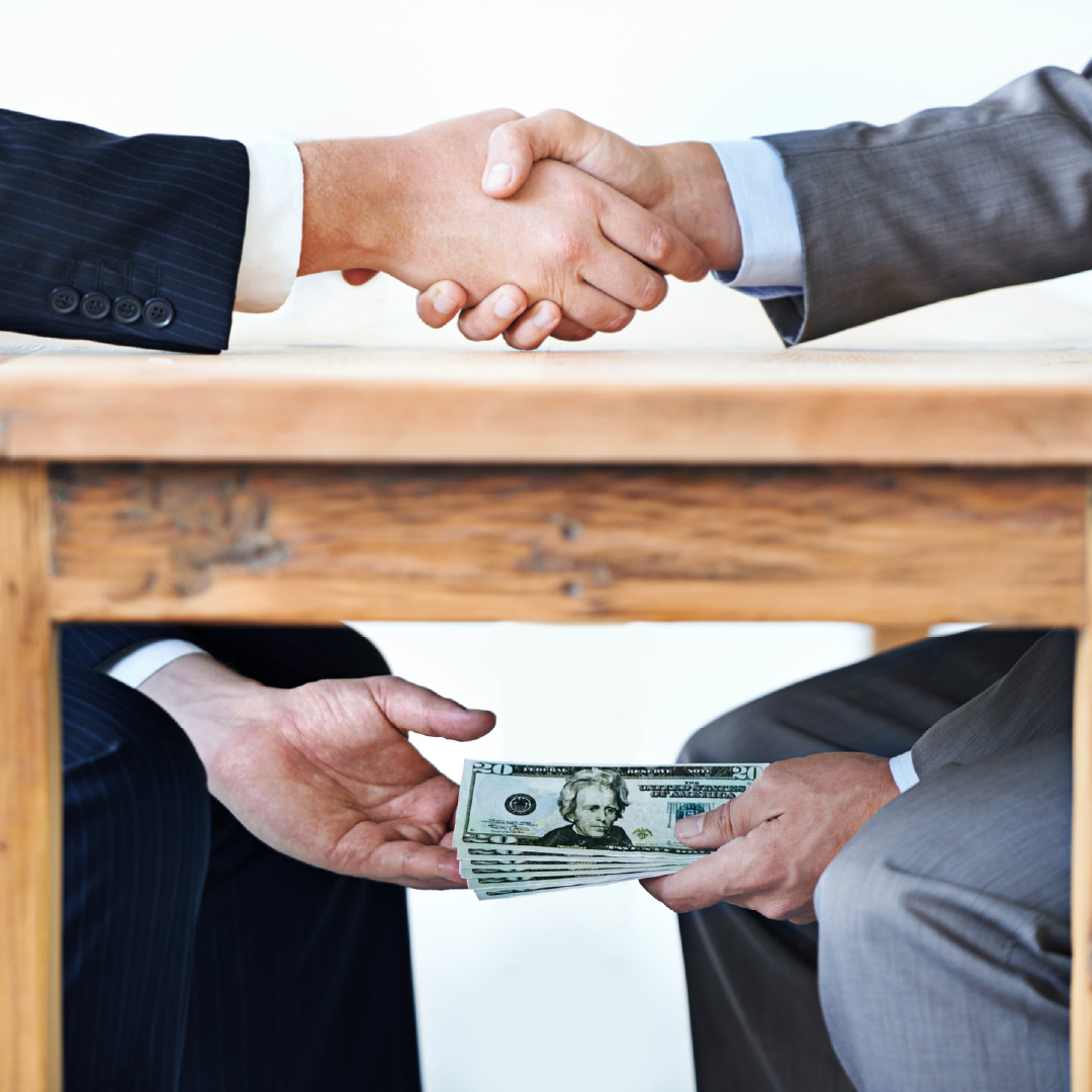 Accepting kickbacks or bribes is another form of business fraud, depicted as an under the table deal. 