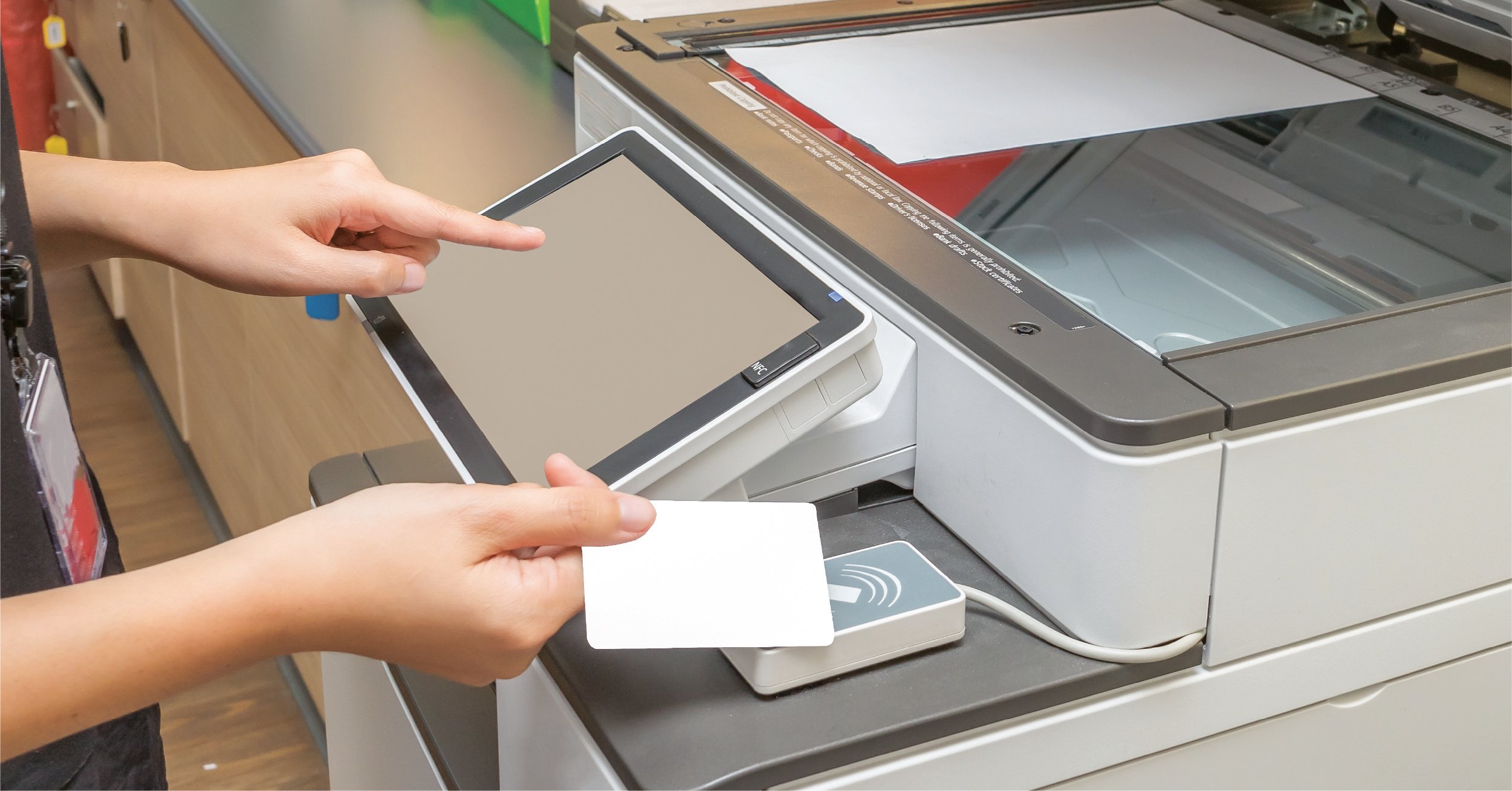 An employee in a law firm uses a badge to release a print job at the networked printer.