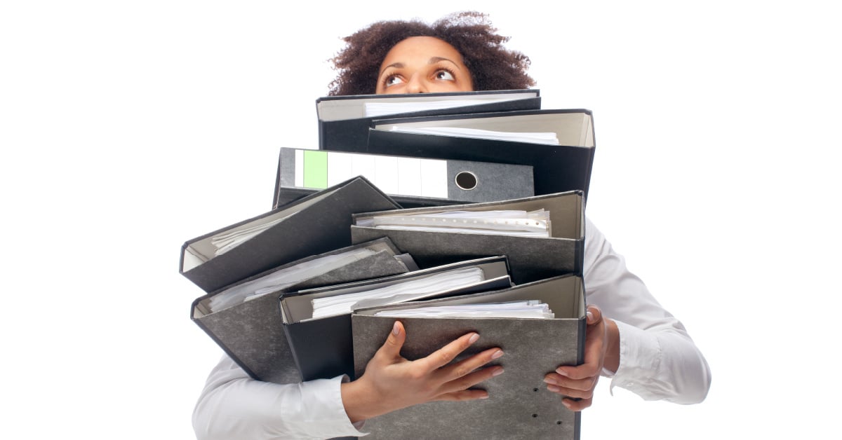 A college student struggles to carry multiple binders of printed documents.